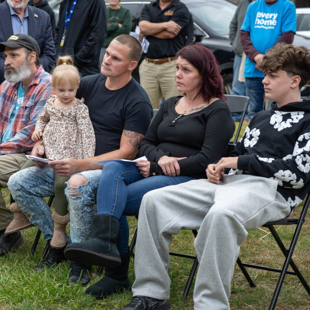 Family sitting in folding chairs listening to speaker