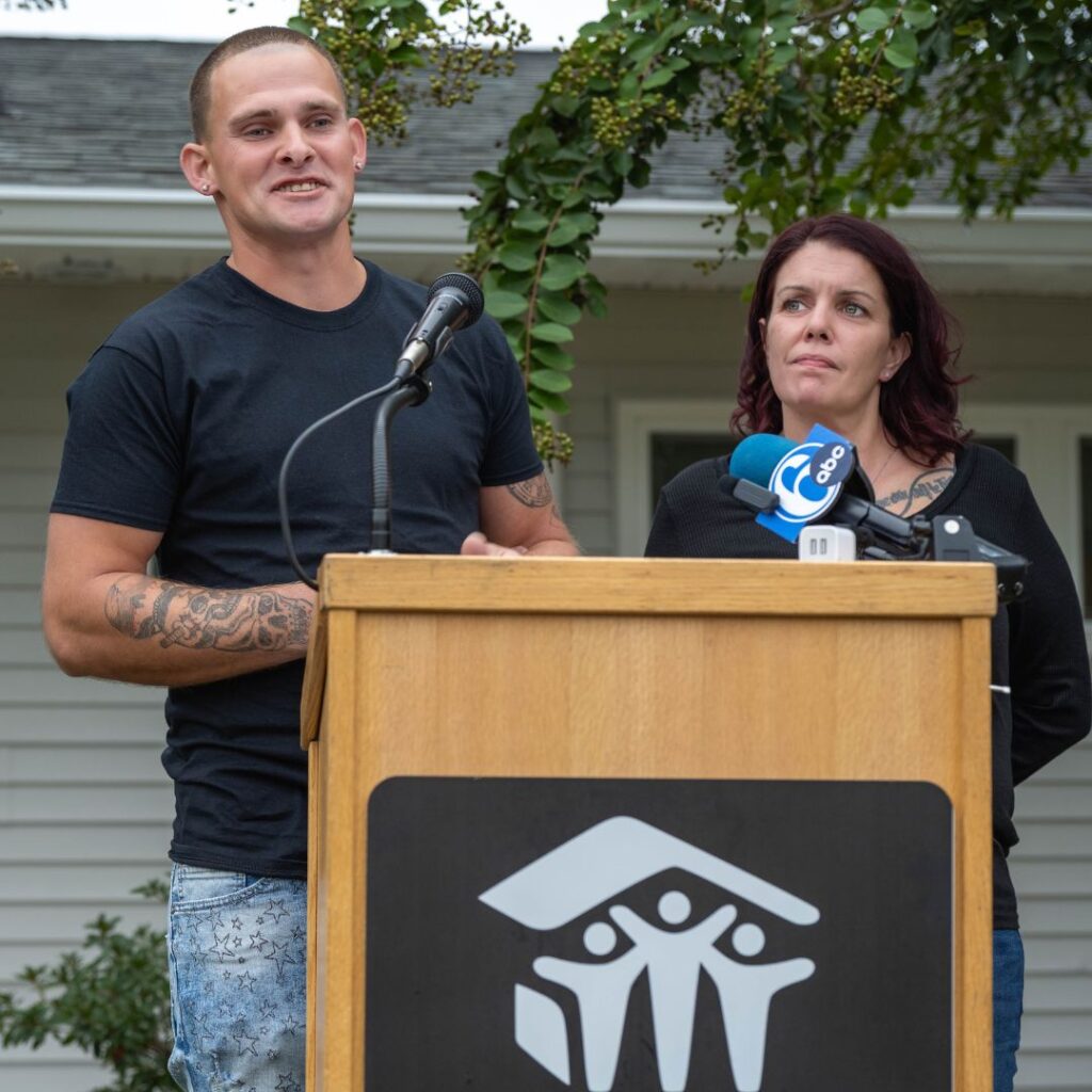 person in black tshirt speaking at microphone