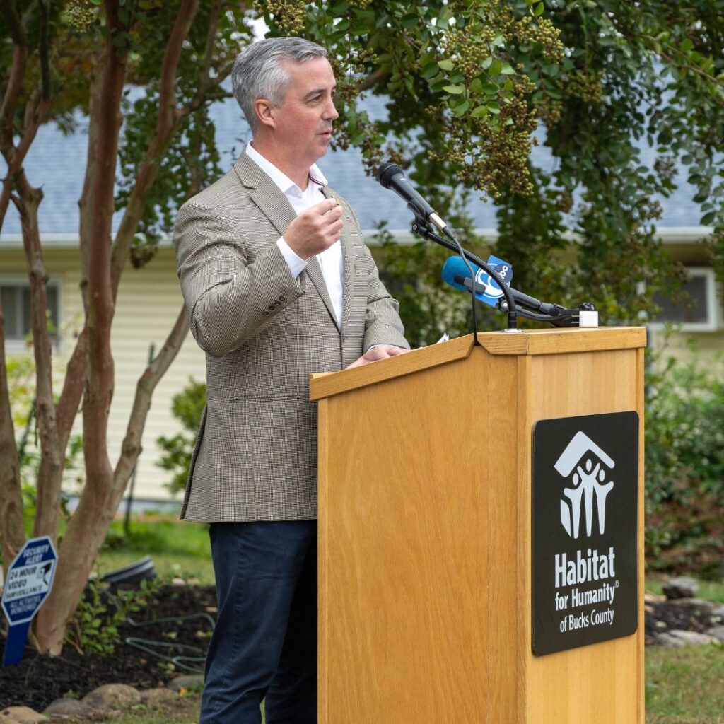 person in gray blazer speaking at podium